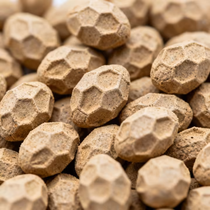 Extreme close-up view of hexagonal termite frass pellets, showing their distinct shape and gritty texture.